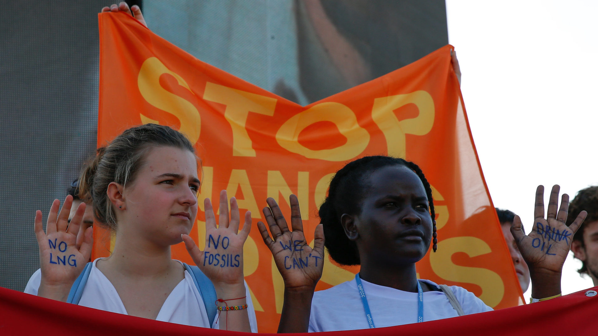 Aktivist*innen auf der COP haben ihre Hände beschrieben. Auf ihnen steht "NO LNG - NO FOSSILS" und "We can't drink oil" - Foto: UNFCCC / Kiara Worth