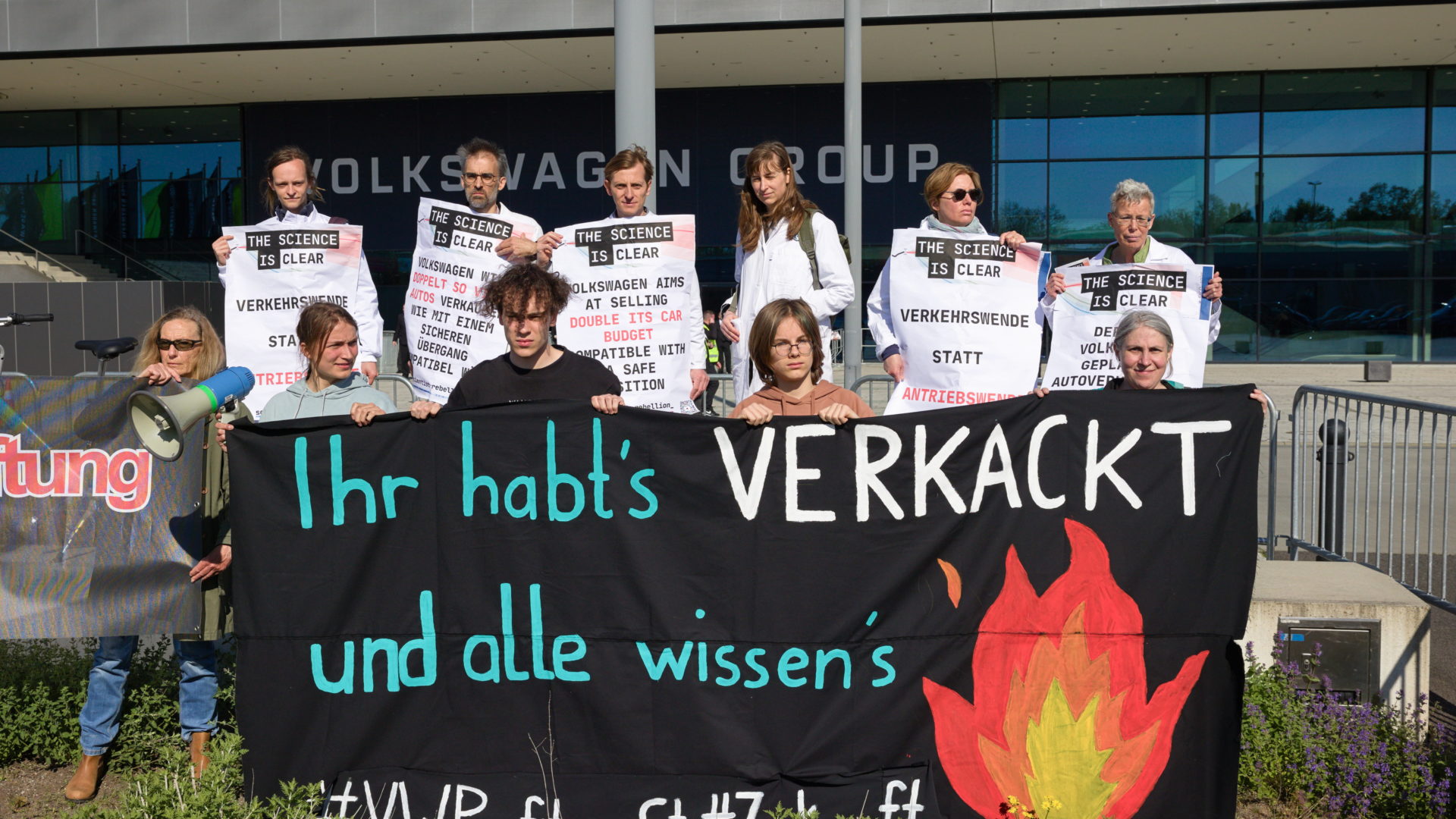 Kundgebung vor der VW Hautversammlung, AKtivist*innen halten ein Transparent mit der Aufschrift "Ihr habt's verkackt und wir wissen's #VWProfitgierStattZukunft